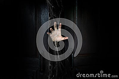 The hand of the man holding the stick from the wooden door from the inside of the dark Stock Photo