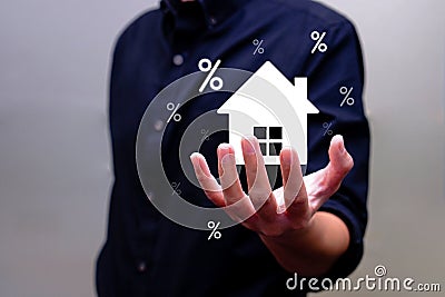 Hand of man holding virtual house with percentages around it. Interest rate finance and house loan concept. Stock Photo