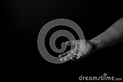 Hand of a man palm up reaching, on black background, giving a helping hand. Give me your hand concept. Stock Photo