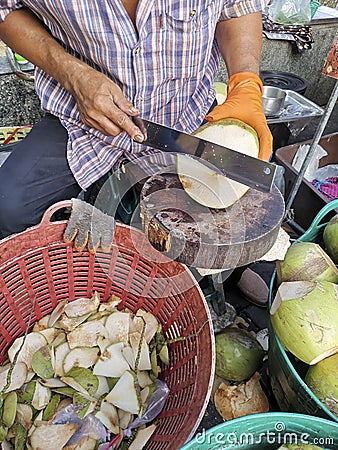 Hand man peeling coconut with knife Stock Photo