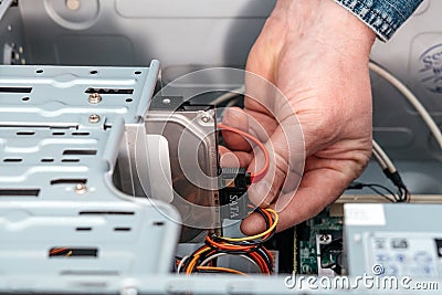 Hand of man plugging SATA Serial AT Attachment, Serial ATA data cable in hard drive device. Computer bus interface to connect ma Stock Photo