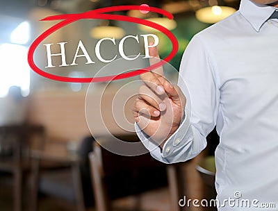 Hand of man touching text HACCP with white color on blur interior background. Stock Photo