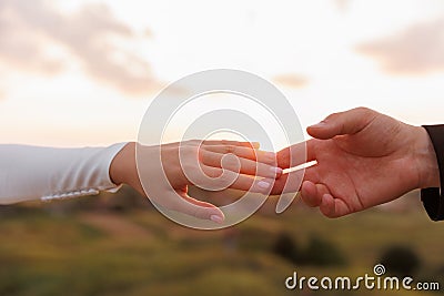Hand of man and woman reaching and touching to each other with love on nature sunset sky background. Valentines day Stock Photo