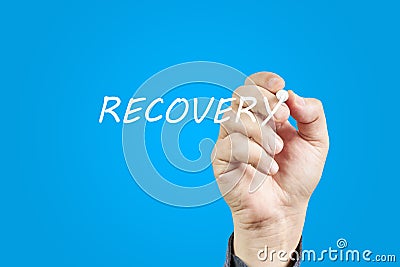 Hand of man writing the word Recovery on a blue background Stock Photo