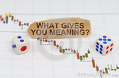 On the trading charts, there are dice and pieces of paper with the inscription - WHAT GIVES YOU MEANING Stock Photo