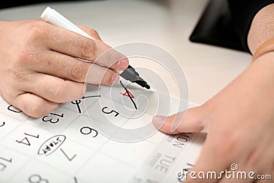 Hand is marking cross days off the black marker in the calendar Stock Photo