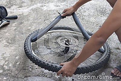 Hand of a mechanic is changing the tires of the bicycle. Stock Photo