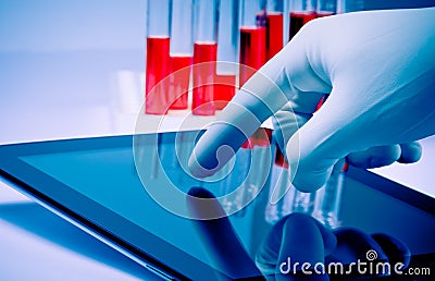 Hand in medical blue glove touching modern digital tablet in laboratory Stock Photo
