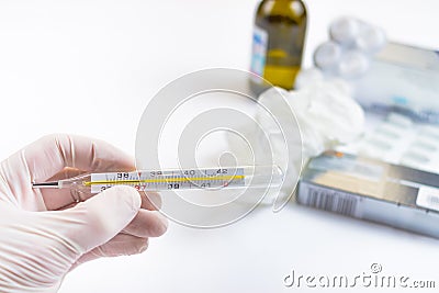 Hand in medical glove holding a thermometer with pills and medic Stock Photo