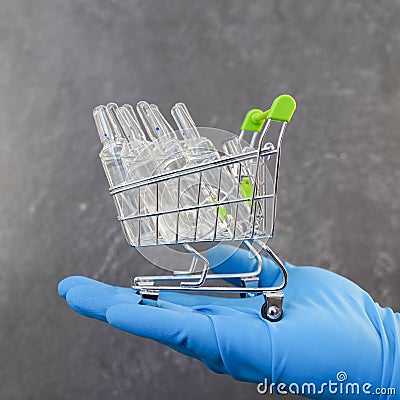 A hand in a medical glove holds a vaccine in a grocery cart Stock Photo