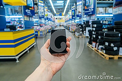 Hand with mobile phone on a background of a blurry shopping center. Stock Photo