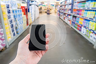 Hand with mobile phone on a background of a blurry shopping center. Stock Photo
