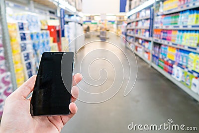 Hand with mobile phone on a background of a blurry shopping center. Stock Photo