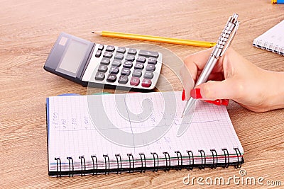 Hand, notepad and calculator on wooden Stock Photo