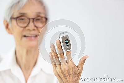 Hand of old elderly with fingertip pulse oximeter on finger for examination of the lung disease,checking for Coronavirus COVID-19 Stock Photo