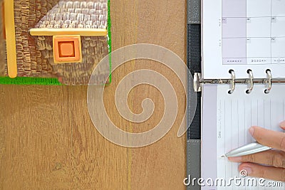 hand organizing plan with notebook. house model on wooden desk Stock Photo
