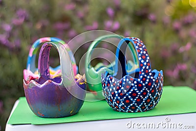 Hand-painted Easter egg baskets on a green pedastal in front of purple lavender flowers Editorial Stock Photo