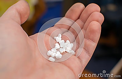 On the palm of the person cute white pills with hearts Stock Photo