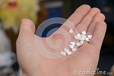 On the palm of the person cute white pills with hearts Stock Photo