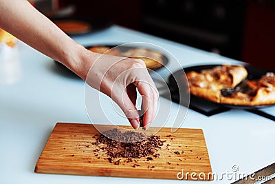 The hand of pastry chef with grated chocolate. Going to sprinkle the cake Stock Photo