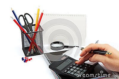 Hand with pen, calculator, notepad and office supplies. Stock Photo