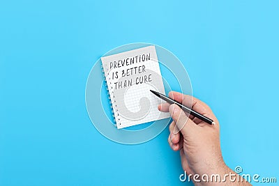 Hand with a pen writing in a notebook Prevention is better than cure Stock Photo