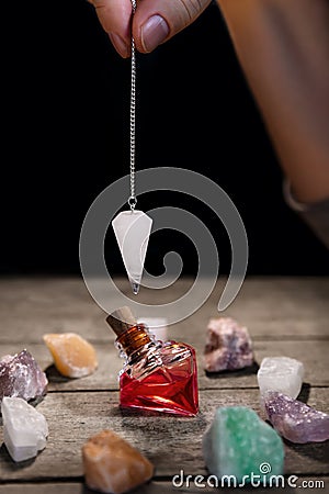 Hand with pendulum, an elixier and healing stones, fortuntelling and horoscope Stock Photo