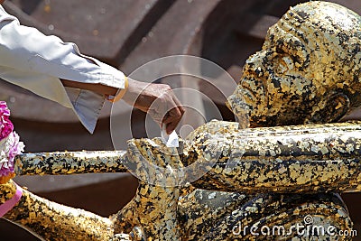 Hand of people gild to Buddha statue gold covered thinly with go Stock Photo