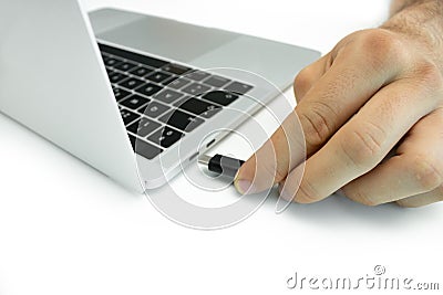 Hand of a person connecting an external hard drive to his laptop, white table Stock Photo