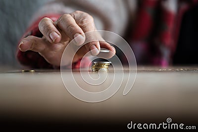 Hand of person putting coin on pile Stock Photo