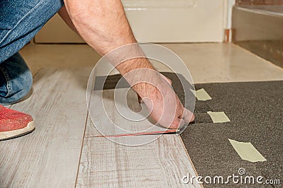 Hand of a person working that has several fingers amputated. Person with dirty clothes laying a floor in his house. Physical disab Stock Photo