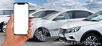 Hand with phone on a background of rows of cars. Car sales. Stock Photo