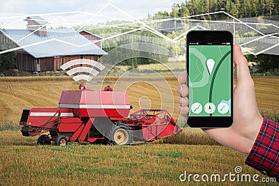 Hand with phone. On the screen control interface of the self driving combine harvester. Stock Photo