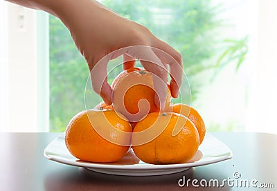 Hand picking orange on dish Stock Photo