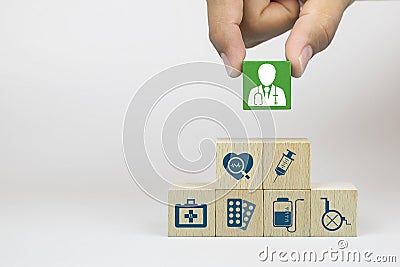 Hand picking up doctor icon on cube wooden toy blocks with medical icons stacked. Stock Photo