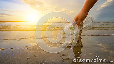 The hand is picking up trash on the beach, the idea of environmental conservation Stock Photo