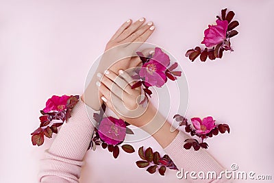 Hand with pink flowers and petals lying on a paper background. Cosmetics for hand skin care. Natural petal cosmetics, essential Stock Photo