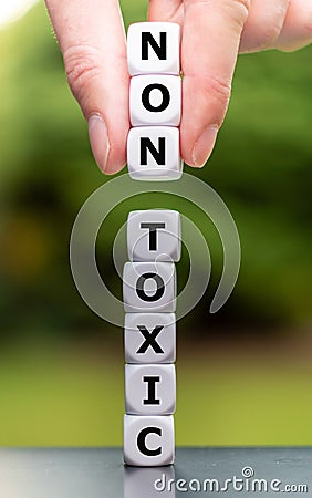 Hand places three dice on a stack and changes the word `toxic` to `non toxic Stock Photo