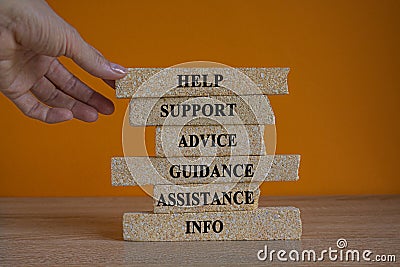 Hand placing a block with word help on top of blocks tower with words 'support, advice, guidance, assistance, info Stock Photo