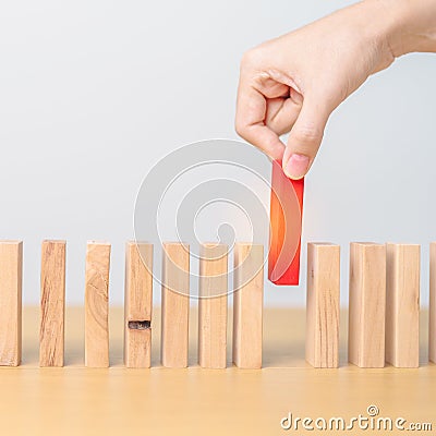hand placing or pulling Red domino wooden block on table. Business planning, Risk Management, Solution, leader, strategy, Stock Photo