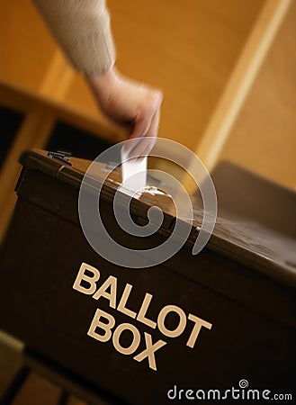 Hand placing vote in ballot box in polling station Stock Photo