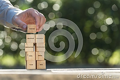 Hand placing wooden building blocks to success Stock Photo