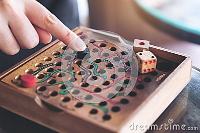 A hand playing wooden Snakes and Ladders game Stock Photo