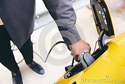 Hand Plugging In Electric Car Outside Office In Car Park Charging Stock Photo