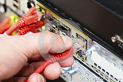 Hand Plugging Network Cable Into Switch In Datacenter Stock Photo