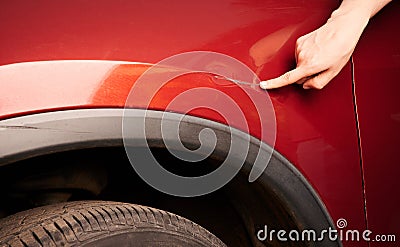 Hand pointing at dent on red car Stock Photo