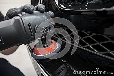 hand with a polishing tool cleaning a bumper on a black car Stock Photo