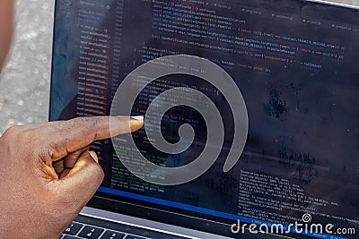 Hand portrait of african web developer pointing finger at line of computer code Stock Photo