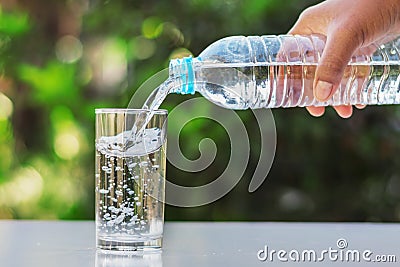 hand pouring drinking water into glass form bottle Stock Photo