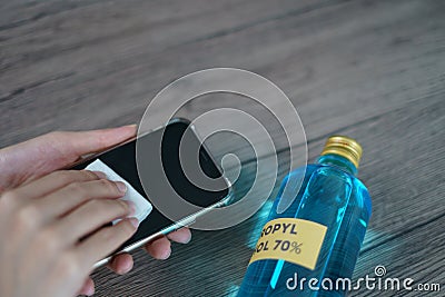 Hand pouring ethyl alcohol from bottle into a cotton piece for clean mobile phone, corona virus or Covid-19 protection Stock Photo